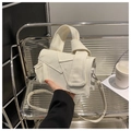 Detail of cream canvas crossbody bag with unique knot folding design and metal stand view - White