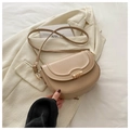 Detail of beige saddle bag with gold ring buckle on cream blazer, showing texture - Khaki