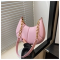 Detailed close-up of pink crescent handbag featuring embossed quilting and gold chain strap - Pink