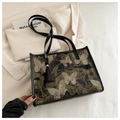 Dettaglio di elegante ricamo a farfalla e nappa sulla borsa tote nera - Nero
