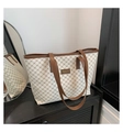 Detalle del bolso tote beige con patrón de cadena sobre mostrador negro y reflejo de espejo - Blanco Roto