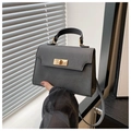 Detailansicht des goldenen Metalldrehverschlusses an einer schwarzen Handtasche - Schwarz
