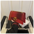 Close-up of red crocodile pattern handbag with gold metal lock and chain strap - Red