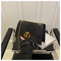 Close-up of black crocodile embossed bag with gold chain and metal CD buckle - Black