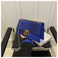 Detail of blue crocodile pattern handbag featuring a gold CD clasp and chain strap - Blue