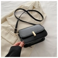 Detail of a matte black leather crossbody bag with a gold rectangular metal buckle - Black