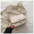 Close-up of cream crossbody bag with gold metal buckle on a beige blazer background - White