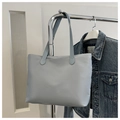 Detalle de un bolso tote azul grisáceo colgado de una percha con chaqueta vaquera - Azul