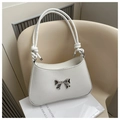 Detailed shot of twisted handle and silver metal bow on a white PU leather shoulder bag - White