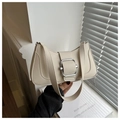 Close-up of cream leather shoulder bag featuring a polished silver buckle and sleek curves - White