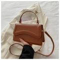 Detail of caramel brown faux leather handbag with wavy flap and thin shoulder strap - Tan