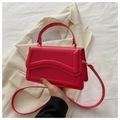 Primo piano di una borsa in pelle rossa con patta a onda e dettagli in metallo dorato - Rosso