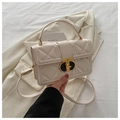 Close-up of quilted beige PU leather bag with premium gold twist lock and elegant texture - White
