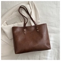 Close-up of vintage brown leather texture and gold rivets on a minimalist tote bag - Brown