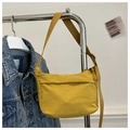 Detail of a bright yellow nylon tote bag with adjustable strap on a metal hanger - Lemon Yellow