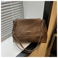 Detalle de la placa metálica dorada sobre un bolso de lona marrón de estilo vintage - Marrón