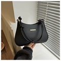 Detail of a minimalist black leather handbag with a gold metal bar and knotted rope handle - Black
