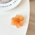 Detail view of orange floral phone grip with translucent petals on a white surface - Orange