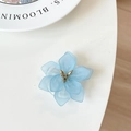 Macro detail of a light blue flower phone grip with matte resin petals and golden stamen - Blue