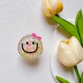 Supporto per telefono glitterato con faccina sorridente e fiocco rosa su vassoio bianco - Supporto Trasparente - Faccina Sorridente con Fiocco di Sabbie Mobili