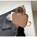 Detalle de bolso beige en piel acolchada con cierre de metal dorado y asas dobles - Caqui