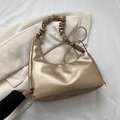 Bolso de hombro chic en oro metalizado con asa fruncida sobre chaqueta blanca - Dorado