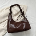 Deep brown glossy cloud shoulder bag featuring pleated strap and decorative bow accent - Brown