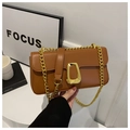 Detail of a brown leather crossbody bag featuring a large gold geometric buckle and chain - Brown