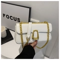 Detail view of white leather crossbody bag with bold gold chain and geometric metal buckle - White