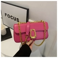 Detailed close-up of glossy magenta crossbody bag with gold chain and unique metal buckle - Rose Pink