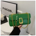 Close-up of bright green leather crossbody bag with gold chain and unique metal clasp - Green