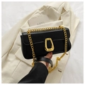 Detalle de bolso bandolera de cuero negro con cadena dorada sobre blazer beige - Negro