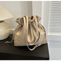 Detail view of a beige nylon drawstring bucket bag with a suede base in a home setting - Khaki