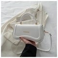 Detail of white PU leather handbag featuring a unique wavy base and gold fashion logo - White