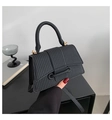 Close-up of black woven texture handbag with golden hardware and leather strap detail - Black