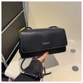 Detailed close-up of a black rectangular crossbody bag featuring a gold brand logo - Black
