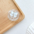 Détail du support de téléphone avec nœud blanc et cœur perlé sur plateau bois - Paillettes Bleu Nœud Cœur