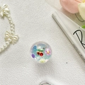 Dettaglio macro del supporto telefono ciliegia con paillettes, fiori e charms sorriso - Margherita Ciliegia - Luce Blu