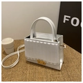 Detail of white leather handbag showing textured stripes and elegant gold metal clasp - White