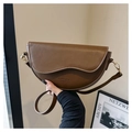 Detail of a brown leather saddle bag featuring fine stitching and gold metal hardware - Coffee