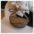 Primer plano de un bolso de cuero marrón sostenido por una modelo en un sillón suave - café