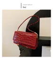 Detail der roten Umhängetasche mit Steinmuster, Glanzfinish und goldfarbenen Metallteilen - Rot