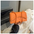 Detail van een feloranje gewatteerde baguette tas met zilveren hardware en handvat - Oranje