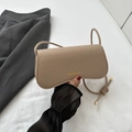 Beige crocodile embossed underarm bag with gold lettering shown in hand - Khaki