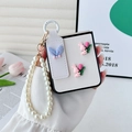 Close-up of white leather Z Flip case with pearl wrist strap, pink bunny and tulip charms - White Cross-Grain Tulip Rabbit Ear With Pearl Chain / Samsung ZFlip3