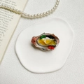Primer plano de un soporte para móvil con forma de ostra sobre un plato cerámico - Ostra de Color 3D