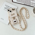 Detalle de funda iPhone de cuero beige acolchado con cadena y amuleto de perfume - Albaricoque / iPhone 15 Promax