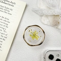 Nahaufnahme einer Handyhalterung mit einer gelben Trockenblume und goldenen Metallperlen - Harzständer - Gedrehter Ring Echte Blume / Gelb