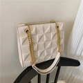 Borsa tote beige trapuntata con trama geometrica e catena dorata sulla sedia - Bianco