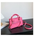 Detailed view of pink leather handbag featuring decorative zippers and long tassels - Pink